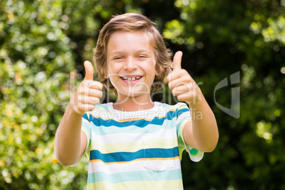 A little boy is putting up their thumbs in the air
