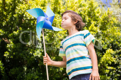 A little boy is blowing on pinwheel