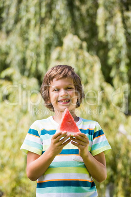 A little boy is smiling with a watermelon