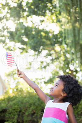 A little girl is holding an american flag in the air