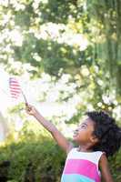 A little girl is holding an american flag in the air