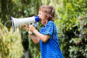 A little boy is screaming with a megaphone