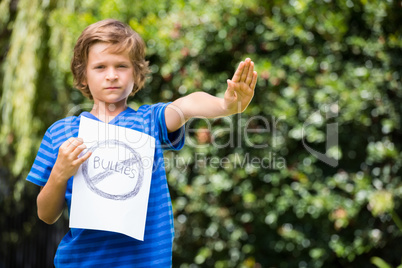 Serious boy saying stop with his hand and holding a message