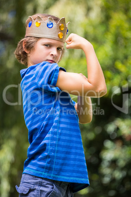 Portrait of cute boy with a crown showing his muscle