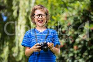 Cute boy with glasses holding a camera
