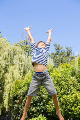 Cute boy jumping with raised arms