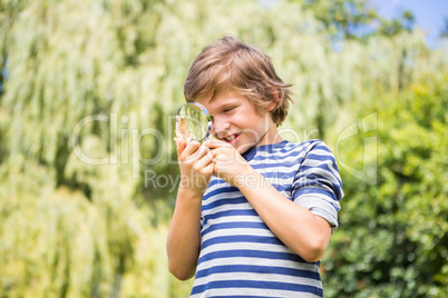Portrait of happy boy looking a leaf with magnifying glasses