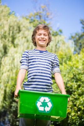 Low angle view of happy boy holding a recycling box