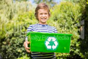 Portrait of cute boy smiling and holding a recycling box