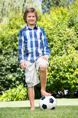 Cute boy smiling and posing with his foot on a soccer ball