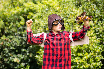 A kid is playing with a plane dressed with a costume of aviator