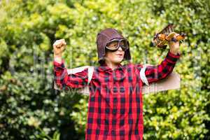 A kid is playing with a plane dressed with a costume of aviator