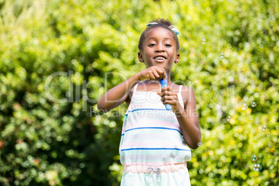 Cute mixed-race girl smiling and playing with bubbles