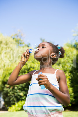 Cute mixed-race girl smiling and playing with bubbles