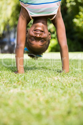 Portrait of a cute mixed-race girl smiling and doing a headstand