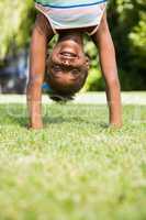 Portrait of a cute mixed-race girl smiling and doing a headstand