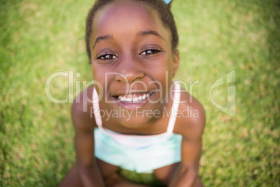 Portrait of a cute mixed-race girl smiling and sitting on grass