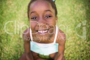 Portrait of a cute mixed-race girl smiling and sitting on grass