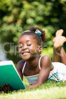 Smiling cute mixed-race girl lying and reading a book