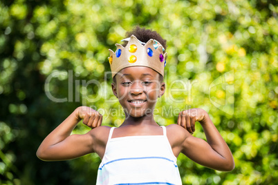 Cute mixed-race girl holding a crown and showing her biceps