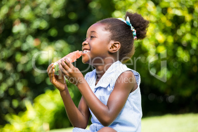 Cute mixed-race girl sitting and eating a watermelon