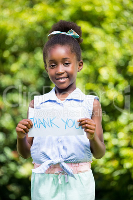 Cute mixed-race girl smiling and holding a paper with thank you