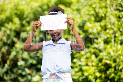 Cute mixed-race girl holding a paper with help message