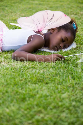 Cute mixed-race girl wearing a fairy dress and sleeping on grass