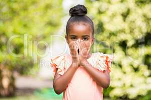 Little girl hiding her mouth at park