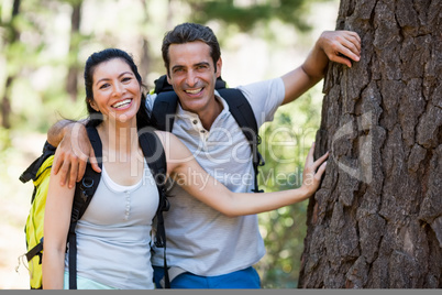 Couple smiling and resting against a tree