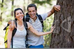 Couple smiling and resting against a tree