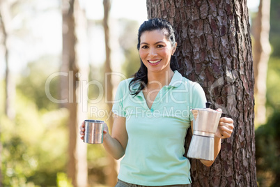 Woman smiling and holding a cup and a coffee maker