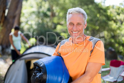 Man smiling and holding a sleeping bag