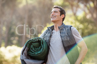 Man smiling and holding a sleeping bag