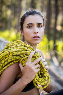 Woman unsmiling and sitting with climbing equipment