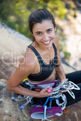 Woman smiling and sitting with climbing equipment