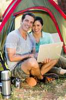 Couple smiling and holding a laptop
