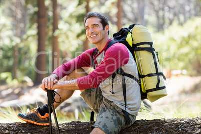 Man hiker smiling and sitting on a tree