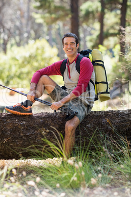 Man hiker smiling and sitting on a tree