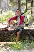 Man hiker smiling and sitting on a tree