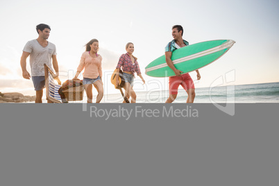 Friends carrying a surfboard and basket