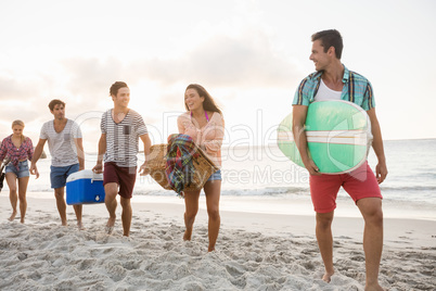 Friends carrying a surfboard and basket