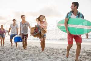 Friends carrying a surfboard and basket