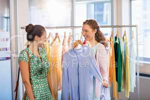 Woman selecting an apparel while shopping for clothes with her friend