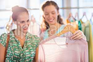 Woman selecting an apparel while shopping for clothes with her friend