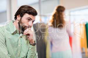 Bored man waiting his wife while woman by clothes rack