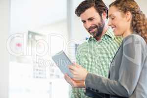 Businessman and businesswoman discuss using digital tablet