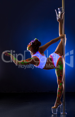 Pole dance. Flexible girl with uv bodyart posing
