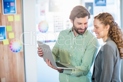 Businessman and businesswoman discuss using computer