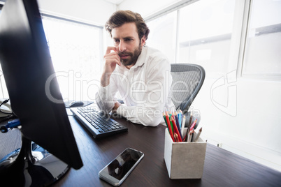 A pensive man looking at his computer